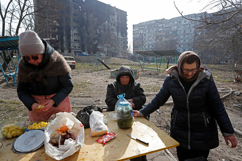 Местные жители готовят еду возле разрушенного жилого дома в Мариуполе