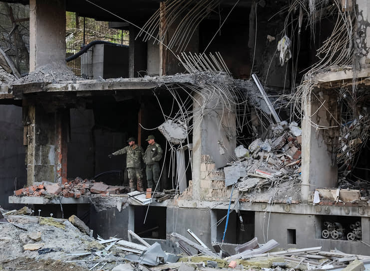 Украинские военнослужащие стоят среди обломков многоквартирного дома в Киеве