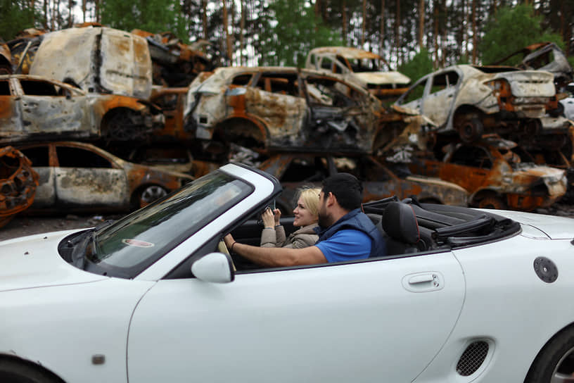 Местные жители в автомобиле рядом с уничтоженными машинами в Буче