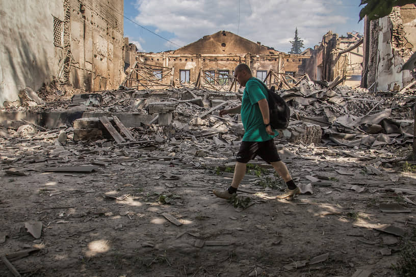 Местный житель идет перед разрушенным зданием в Лисичанске