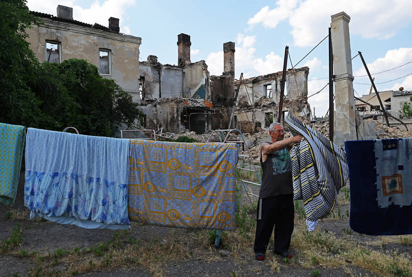 Житель Лисичанска на фоне разрушенного многоквартирного дома