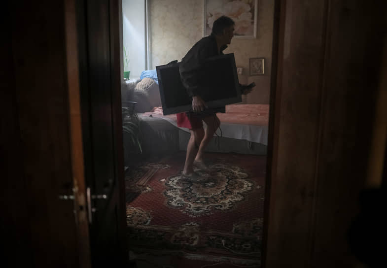 Местный житель выносит телевизор из своего горящего дома в Константиновке