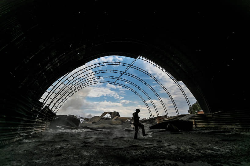 Украинский военнослужащий осматривает сгоревшее зернохранилище на территории фермы в Запорожской области