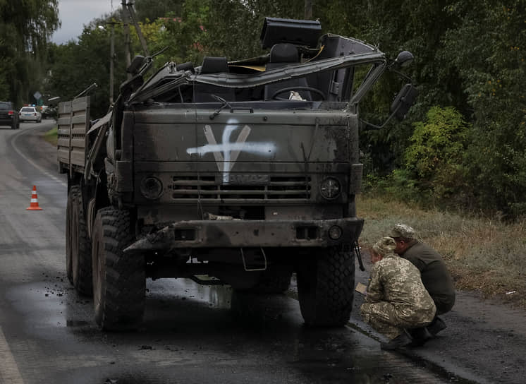 Украинские военнослужащие осматривают поврежденную российскую военную машину в Харьковской области