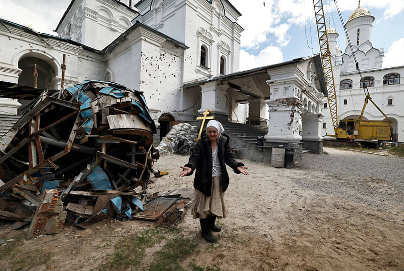 Местная жительница стоит у церкви на территории Свято-Успенской Святогорской лавры в ДНР