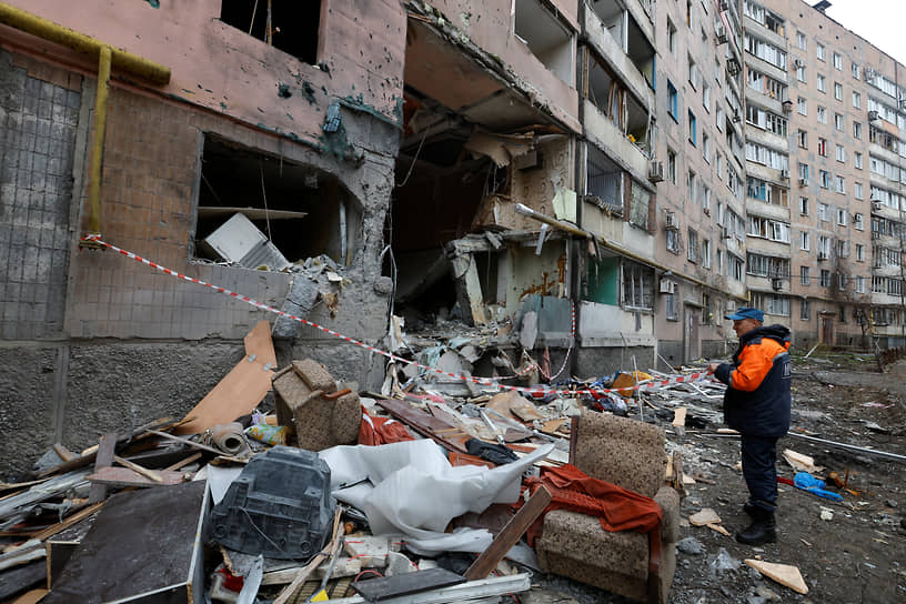 Спасатель стоит у дома, пострадавшего в результате обстрела Донецка