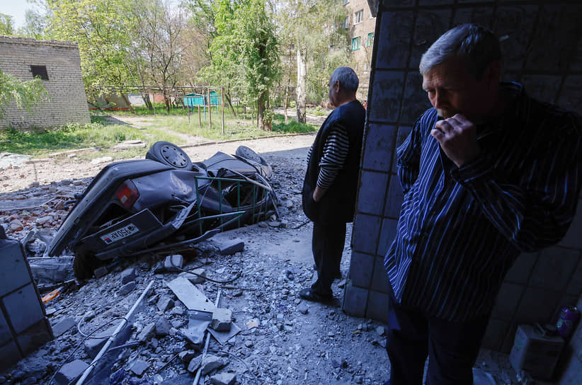 Местные жители возле поврежденного в результате авиаудара автомобиля в городе Ясиноватая