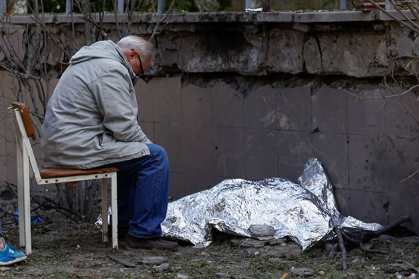 Житель Киева сидит около погибшей при обстреле внучки