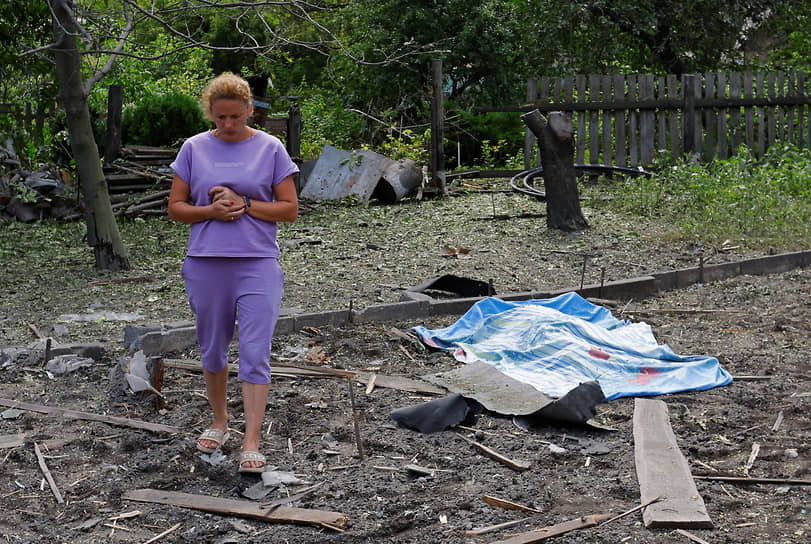 Жительница Донецка стоит рядом с телом погибшей соседки