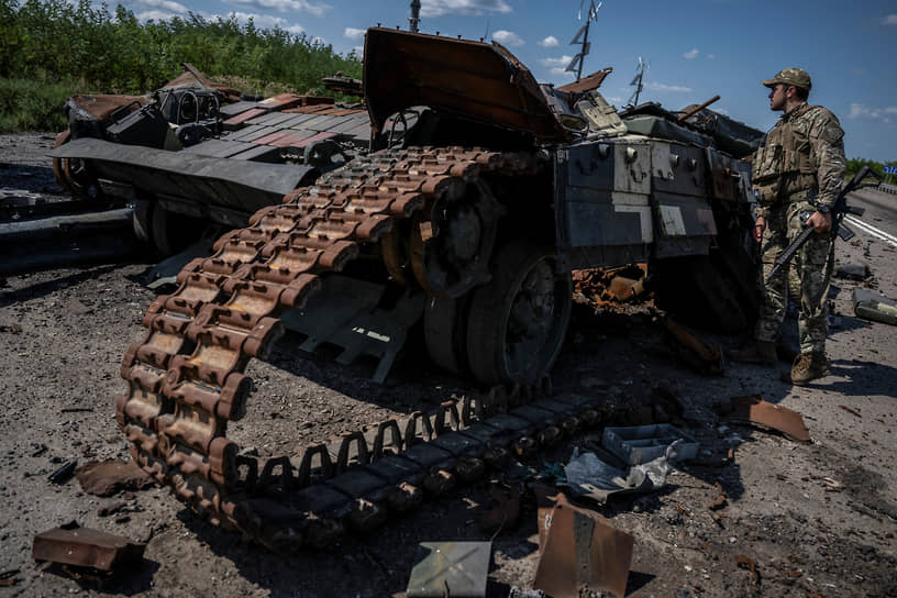 Украинский военнослужащий смотрит на подбитый украинский танк возле села Работино Запорожской области