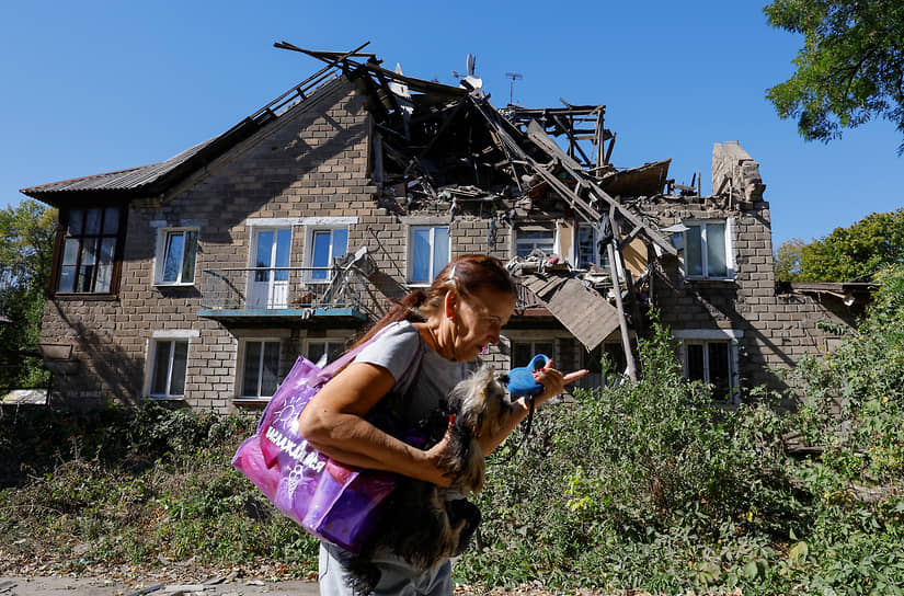 Женщина на фоне поврежденного дома в Донецке