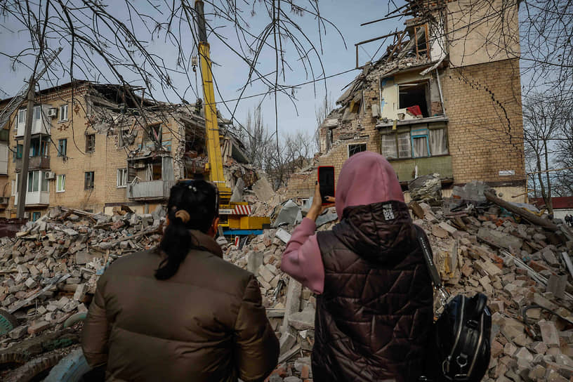 Местные жители фотографируют дома, разрушенные в результате обстрела города Селидово в Донбассе 