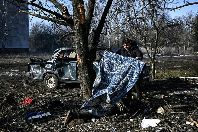 Мужчина накрывает ковром тело после прошедших в городе Чугуев взрывов 