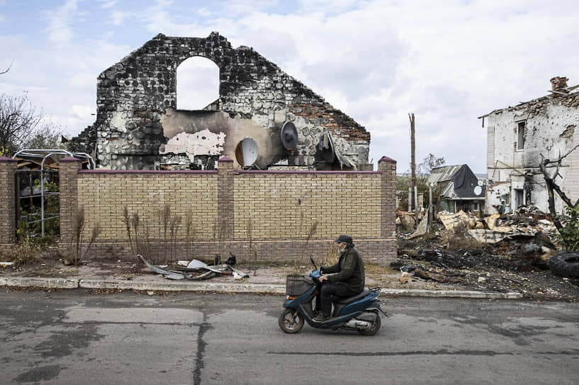 Мужчина проезжает мимо разрушенных домов в поселке Большая Александровка Херсонской области