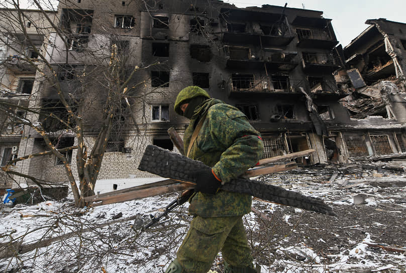 Военнослужащий на фоне поврежденного жилого дома в Волновахе в Донецкой области
