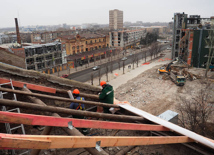 Строители восстанавливают крышу поврежденного жилого дома в Мариуполе