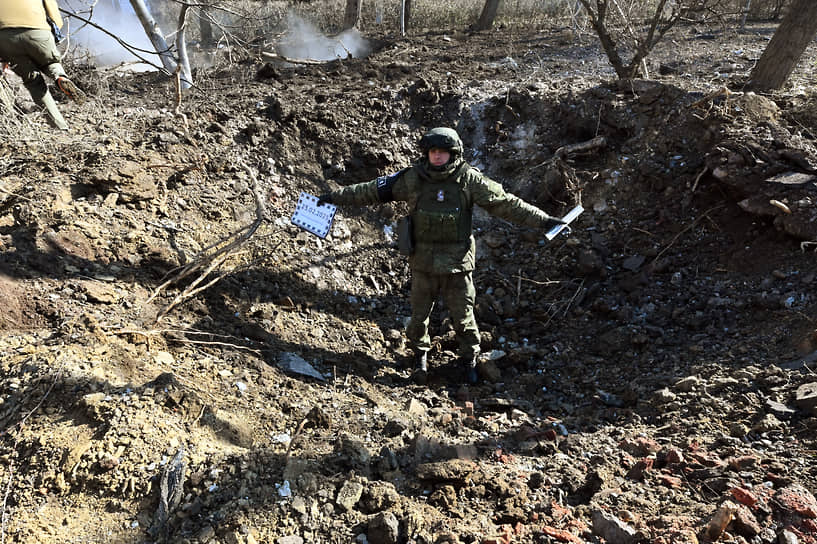 Сотрудник Совместного центра контроля и координации в воронке от попадания снаряда в одном из районов Донецка