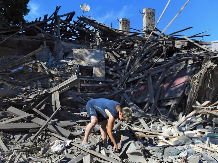 Жительница Донецка разбирает завалы дома, который был разрушен в ходе ракетного обстрела