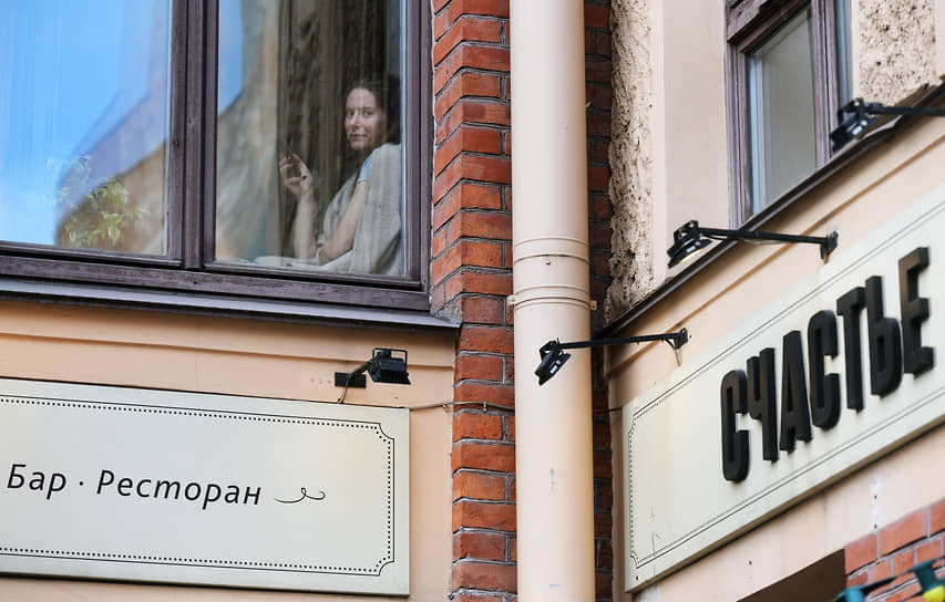 Жительница Санкт-Петербурга смотрит из окна над рестораном «Счастье» 
