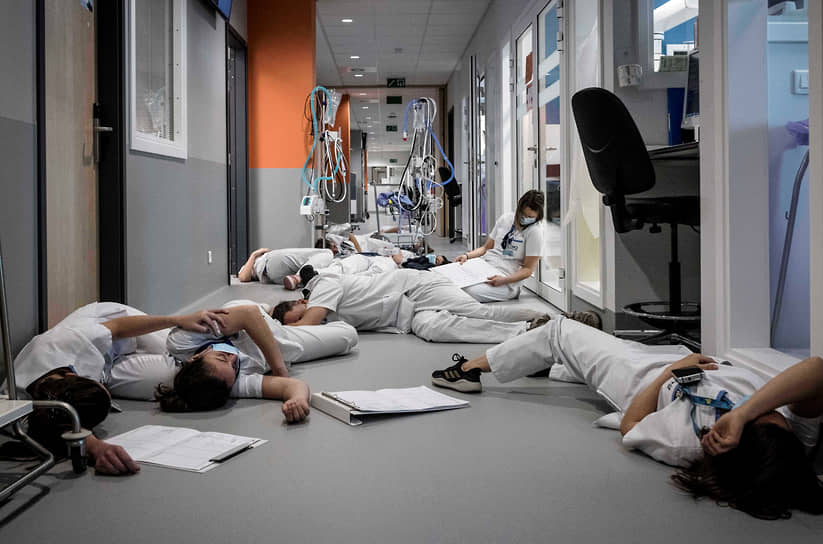 Медсестры и обслуживающий персонал лежат на полу в отделении интенсивной терапии во время демонстрации в Международный день медицинских сестер в больнице Мон-Легия (Бельгия), 2021 год