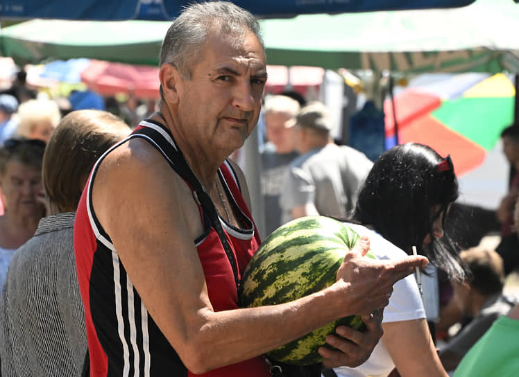 Мужчина покупает арбуз на рынке