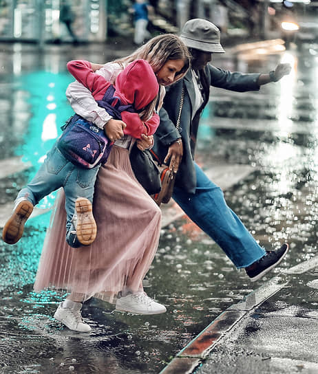 Москва. Женщины перепрыгивают лужу на пешеходном переходе