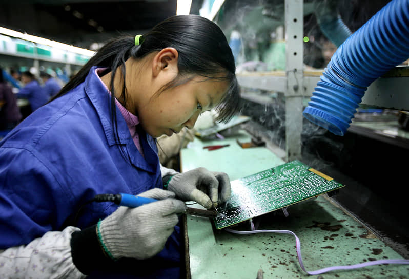 Фошань, провинция Гуандун. Работница паяет электронные компоненты для телевизоров