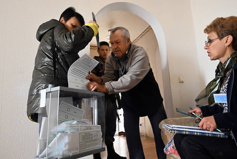 Работники участковой избирательной комиссии и жители во время выездного голосования в жилых домах в ДНР