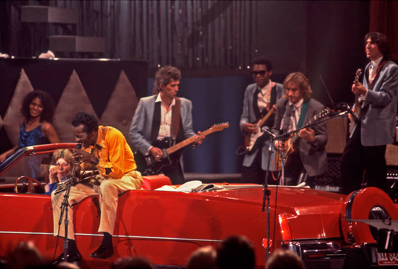 Музыкант Чак Берри (в желтом) выступает, сидя в кабриолете Cadillac, на концерте в честь своего 60-летия вместе с Китом Ричардсом (второй слева), Робертом Крэем (в центре), Джо Уолшем (второй справа) и Джоуи Спампинато, 1986 год