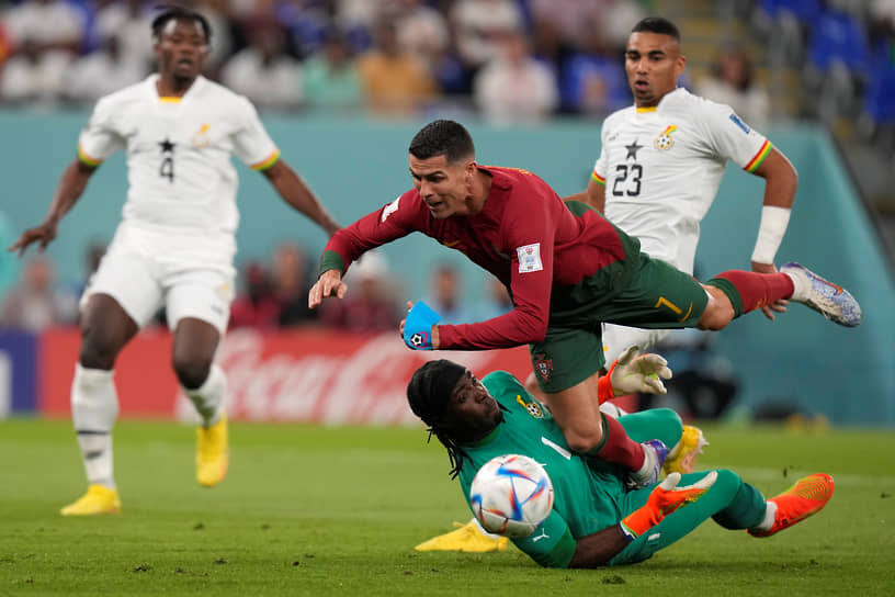 Португальский нападающий Криштиану Роналду (в центре) падает на вратаря сборной Ганы Лоуренса Ати-Зиги (снизу)