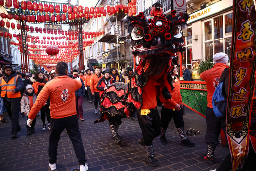 Лондон, Великобритания. Местные жители и танцор в костюме льва отмечают Китайский Новый год