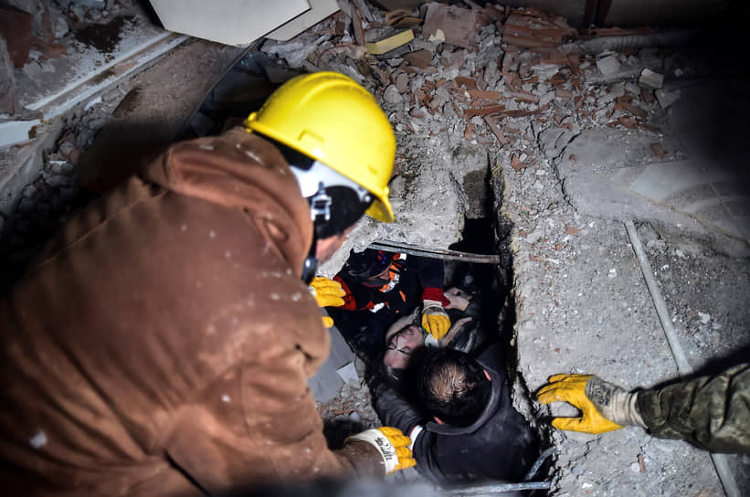 Спасатели эвакуируют женщину из разрушенного здания в Эльбистане (Турция)