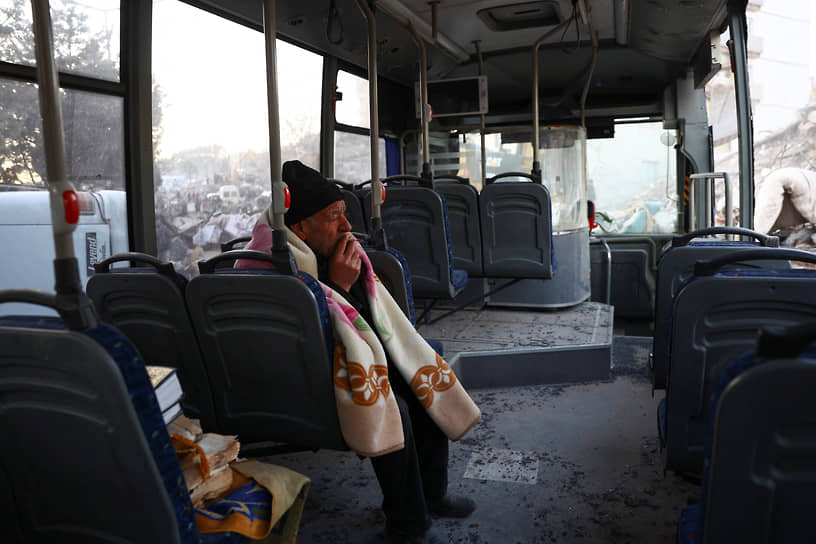 Мужчина сидит в поврежденном автобусе в Кахраманмараше (Турция)