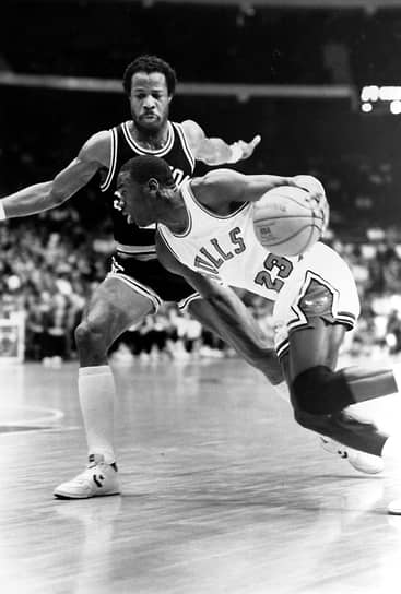 После трех сезонов в NCAA, где Джордан набирал в среднем по 17,7 очков, защитник решил оставить учебу и перейти на профессиональный уровень. 19 июня 1984 года клуб «Чикаго Буллс» выбрал его под третьим номером на драфте НБА&lt;br>
На фото: Майкл Джордан (справа) в матче против «Сан-Антонио Сперс», ноябрь 1984 года
