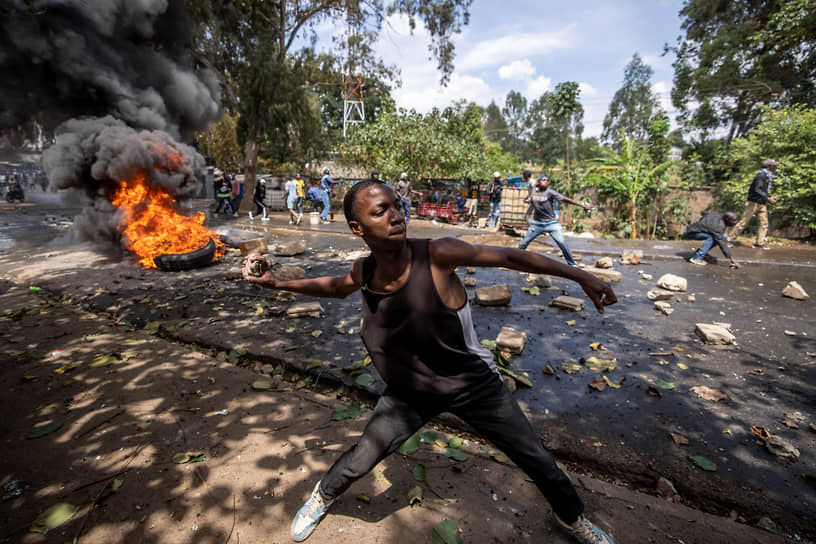 Найроби, Кения. Местный житель, требующий отставки президента, бросает камни в полицию
