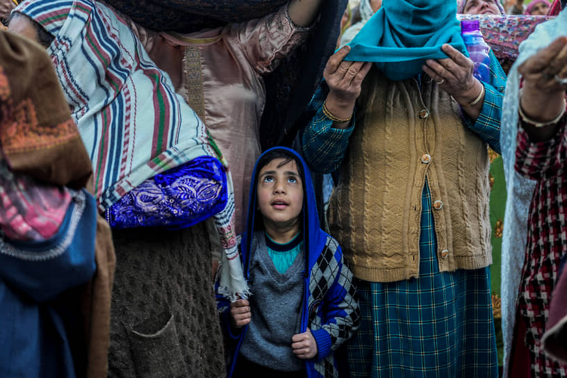 Кашмир. Мальчик-мусульманин стоит со старейшинами в ходе показа священной реликвии, которая, как считается, является волосом из бороды пророка Мухаммеда