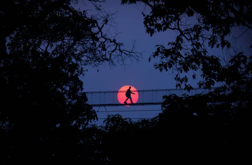 Бхактапур, Непал. Мужчина на подвесном мосту на фоне луны