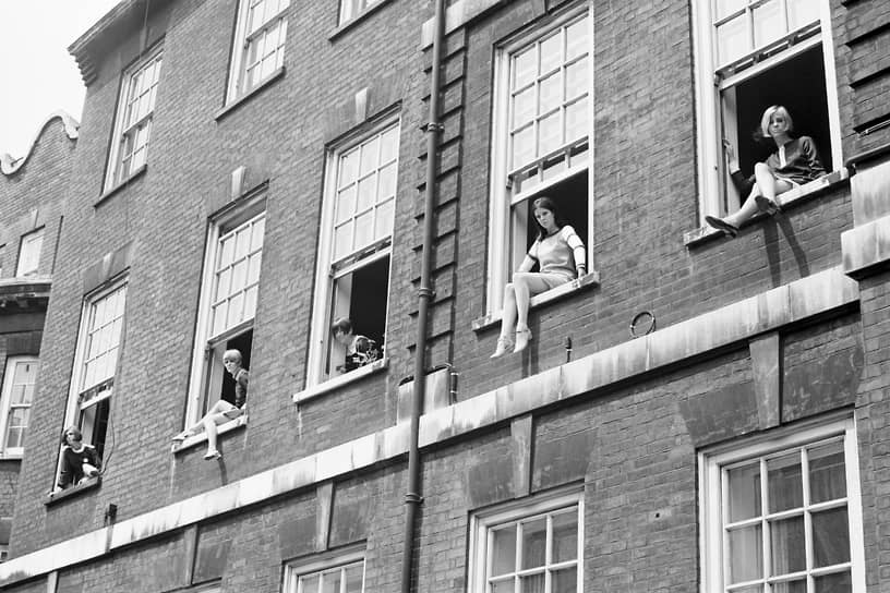 Мэри Куант (в центре) позирует с четырьмя манекенщицами в мини-юбках, сидя на подоконнике номера отеля в Челси в 1966 году