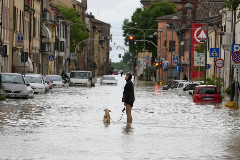 Кастель-Болоньезе, Италия. Мужчина выгуливает собаку на затопленной после дождя улице