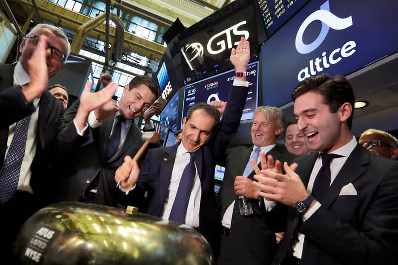 Основатель Altice Патрик Драи (в центре) звонит в церемониальный колокол, когда его компания выходит на IPO. Нью-Йоркская фондовая биржа, 22 июня 2017 года
