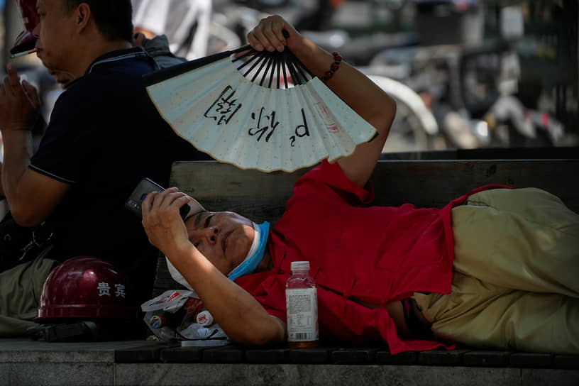 Пекин, Китай. Китаец спасается от жары при помощи веера 