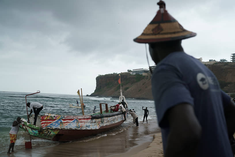 Дакар. Местные жители вытаскивают из воды перевернувшуюся лодку, на борту которой находились мигранты
