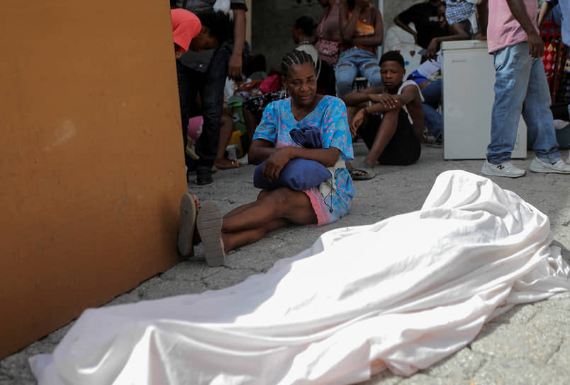 Порт-о-Пренс, Гаити. Местная жительница рядом с телом сына после бандитской атаки
