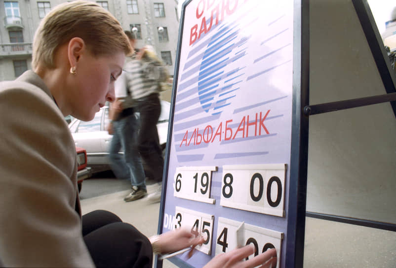 Сотрудница московского банка меняет курс обмена валюты на информационном табло
