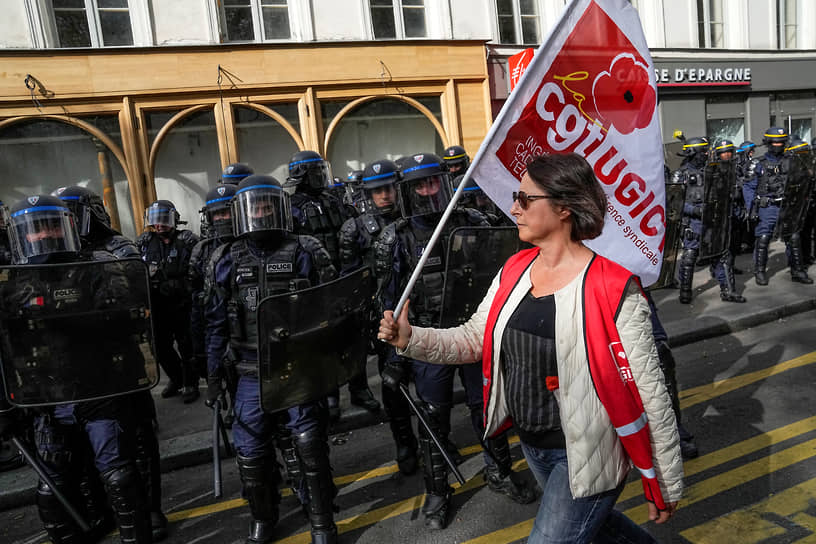 Протестующая с флагом идет мимо полицейских