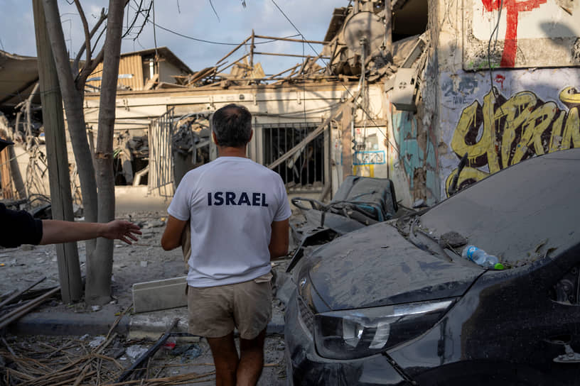 Израильтянин в Тель-Авиве осматривает развалины здания после попадания в него ракеты