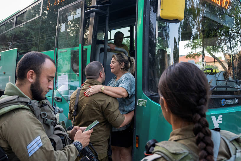 Израильские военные помогают женщине сесть в автобус для эвакуации из города Кирьят-Шмона
