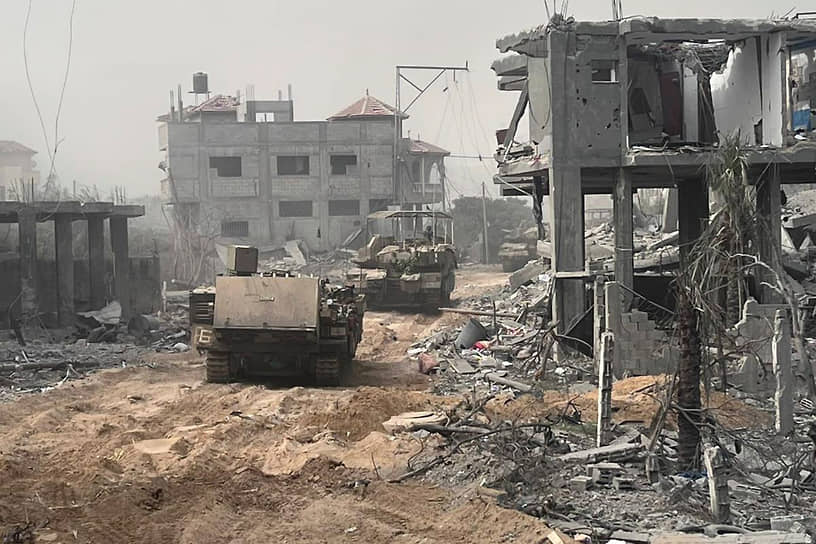 Израильские бронетранспортеры проезжают мимо разрушенных зданий в секторе Газа