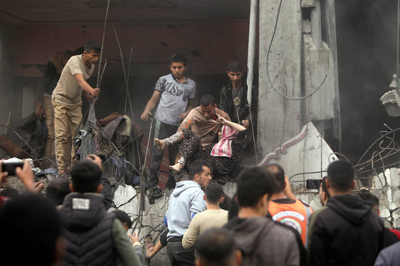 Палестинцы спасают женщину из разрушенного здания после израильских авиаударов в лагере беженцев Хан-Юнис на юге сектора Газа