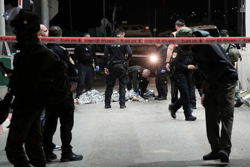 Израильские полицейские осматривают тело палестинца, напавшего на КПП Мазмурия между Иерусалимом и Западным берегом